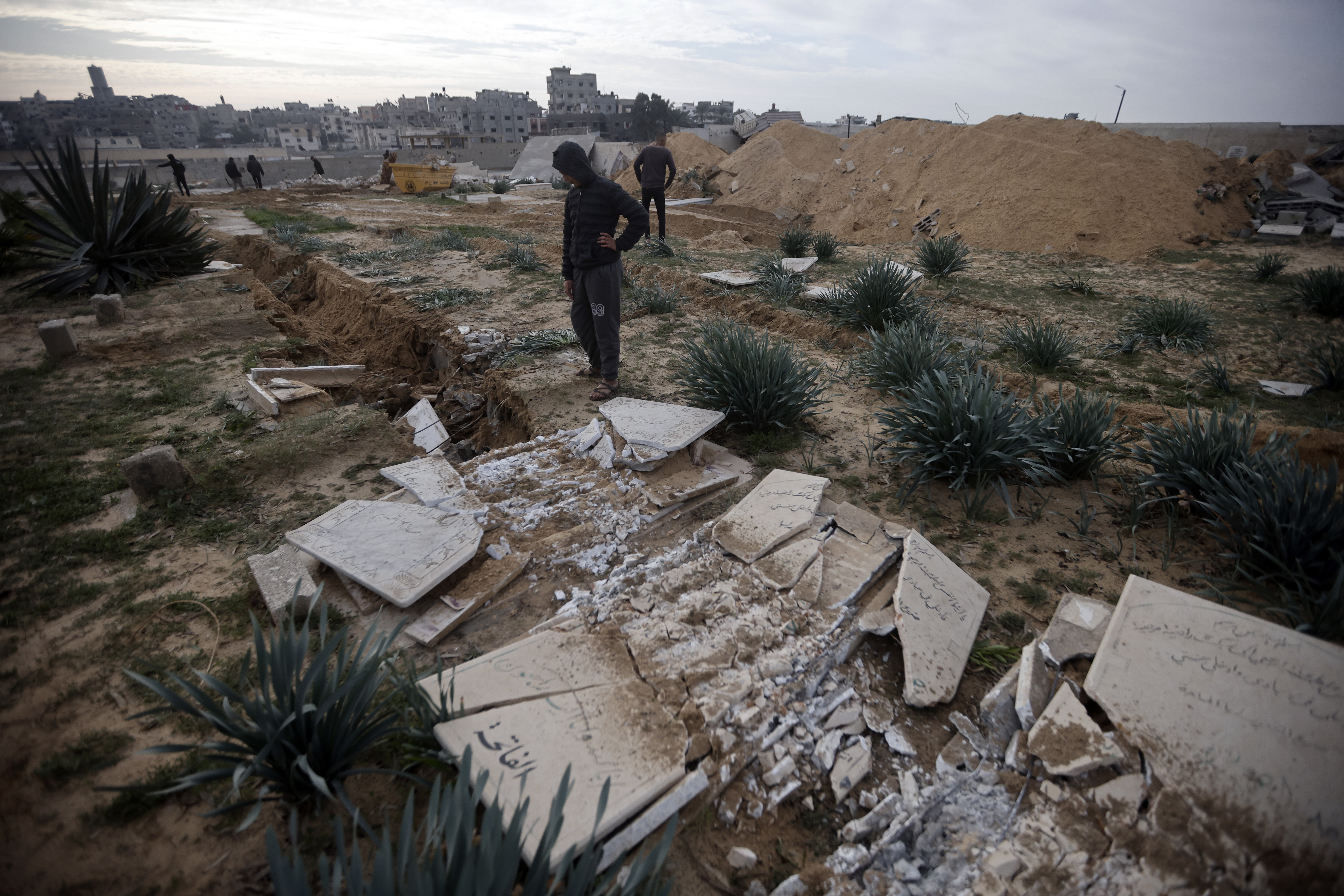 Palestinians inspect damaged graves following an Israeli tanks raid over a cemetery in Khan Younis refugee camp, southern Gaza Strip, Wednesday, Jan. 17, 2024. (AP Photo/Mohammed Dahman)