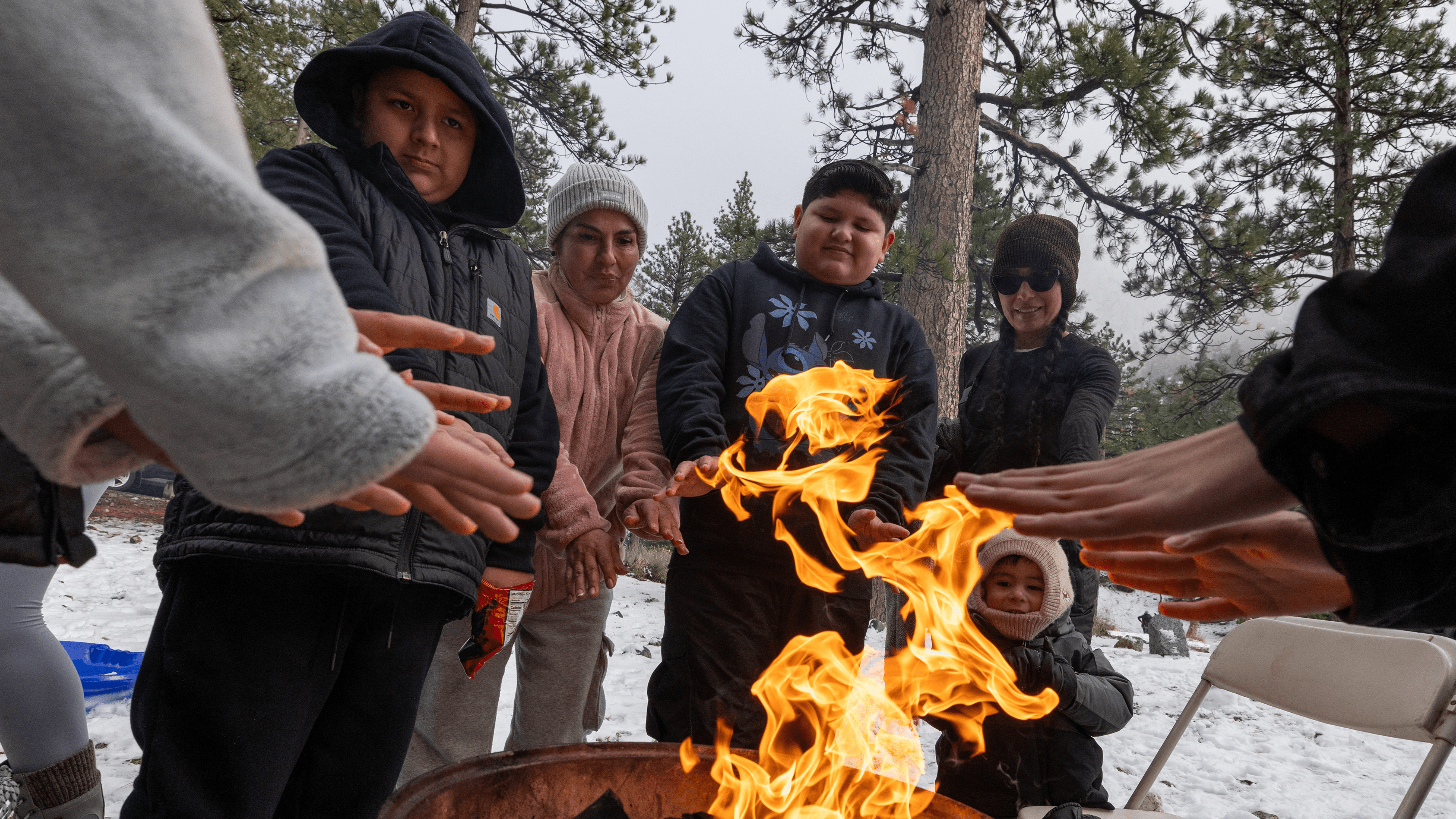 Mt. Baldy, CA - January 03: The Solano family warms their hands around a fire at a chilly Manker Flat Campground on Wednesday, Jan. 3, 2024 in Mt. Baldy, CA.