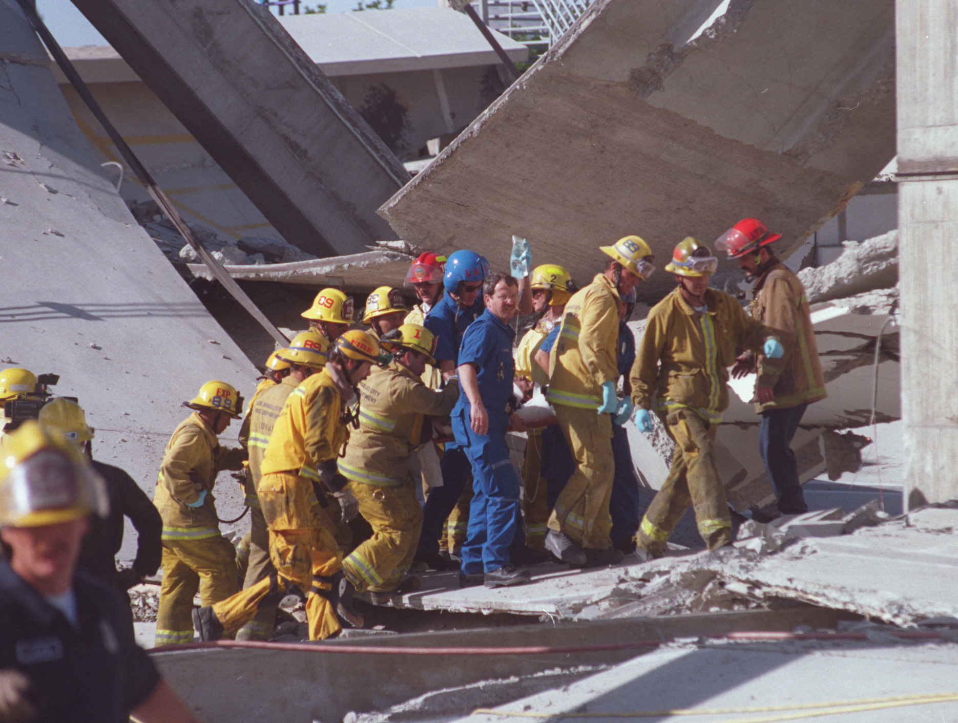 Urban Search and Rescue team members carry Salvador Pena away from the collapsed garage at Northridge Fashion Center where he had been trapped after a structure fell on him during the 1994 earthquake.
